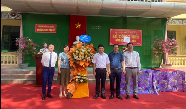 A group of people standing on a red carpet

Description automatically generated